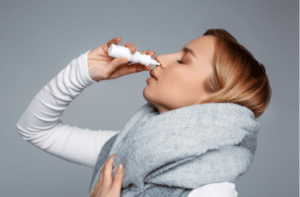 Female wrapped in scarf using nasal spray medicine for runny nose .