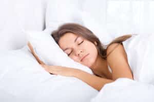 Side view of young woman sleeping in white pillows