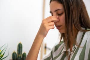 A woman pinching the bridge of her nose, dealing with pain from nasal polyps