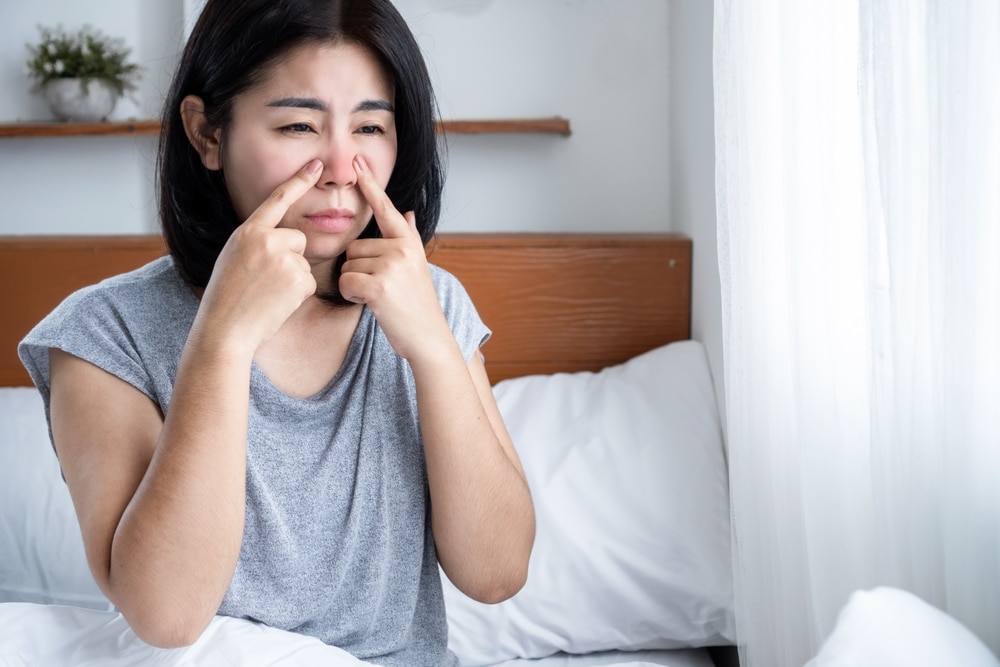 Asian woman suffering from sinus infection having runny nose and stuffy nose